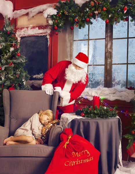 Littlle sovande flicka och Santa Claus tittar på henne Royaltyfria Stockfoton