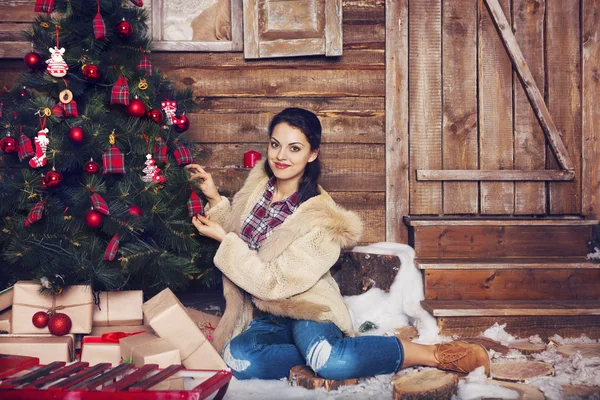 Pretty woman with wearing fur coat sitting near the Christmas tr — Stock Photo, Image