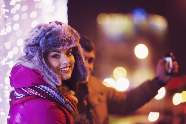 Couple making a selfie with a christmas tree at background — Stock Photo, Image