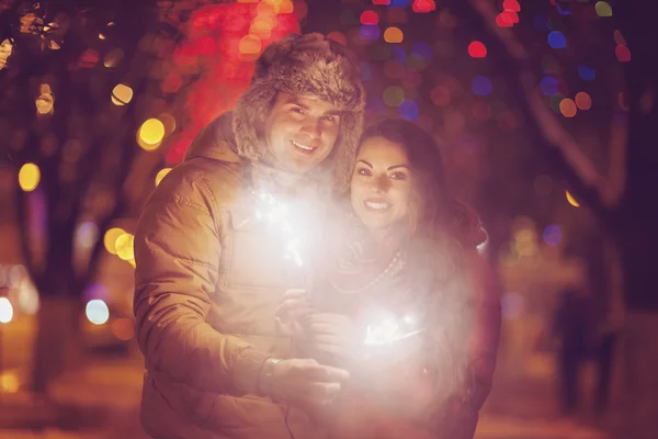 Casal jovem com luz de Bengala olhando para a câmera fora — Fotografia de Stock