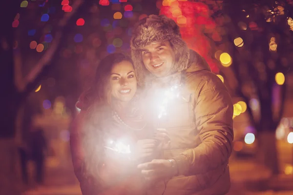 Mladý pár s Bengálsko světlo při pohledu na fotoaparát mimo — Stock fotografie