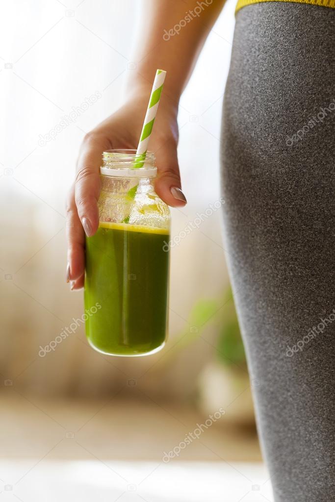 Woman drinking vegetable smoothie after fitness running workout