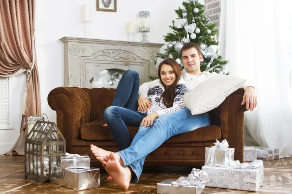 Casal feliz sentado no sofá pela árvore de Natal — Fotografia de Stock