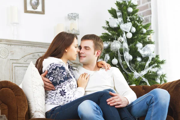 Pareja feliz sentada en el sofá junto al árbol de Navidad —  Fotos de Stock