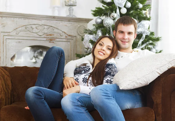 Pareja joven sentada en el sofá junto al árbol de Navidad — Foto de Stock