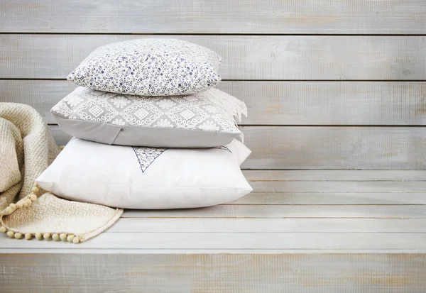 Wygodne poduszki i pled na jasnym tle drewniane — Zdjęcie stockowe