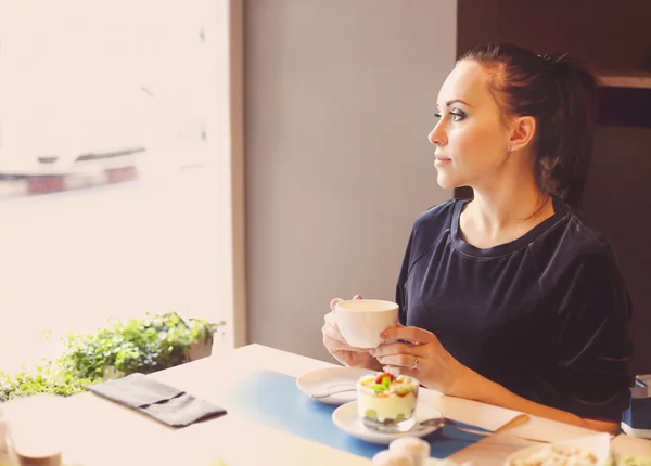 Krásná mladá žena pít čaj v kavárně — Stock fotografie