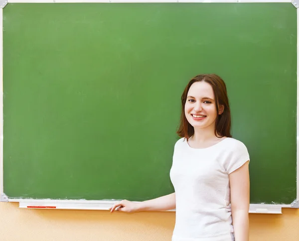 Étudiante debout près de tableau noir propre dans la salle de classe — Photo