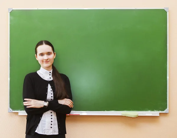 Estudante menina de pé perto de quadro-negro limpo na sala de aula — Fotografia de Stock