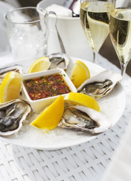 Fresh oysters shell with lemon and glasses of champagne — Stock Photo, Image