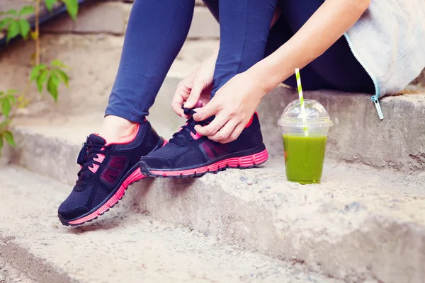 Copo de smoothie desintoxicação verde e mulher atacando tênis de corrida antes w — Fotografia de Stock