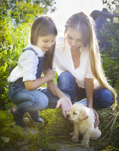 Happy woman and her daughter with puppy of labrador — Stock Photo, Image