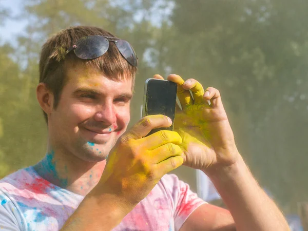 Hombre tomando fotos en el teléfono móvil en el festival de color holi — Foto de Stock