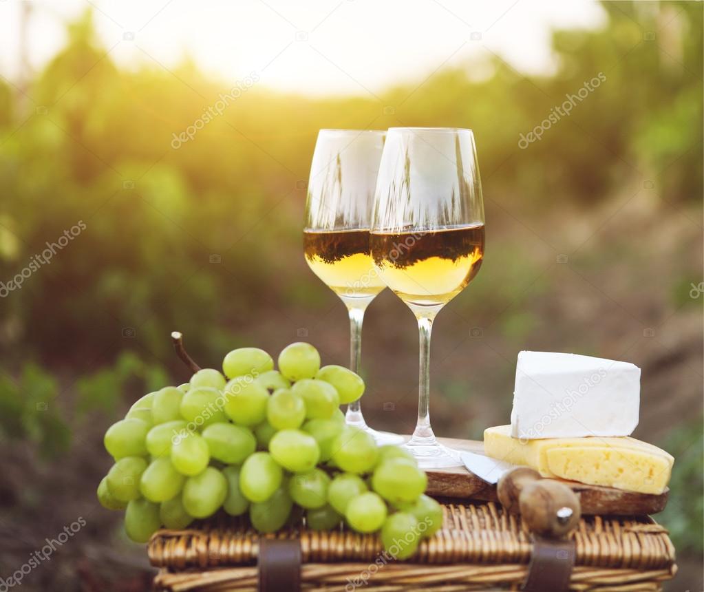 Various sorts of cheese, grapes and two glasses of white wine 