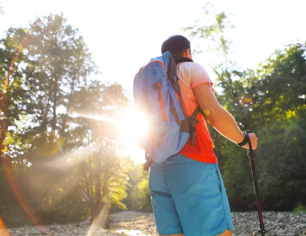 Muž turistiku s backpac a hole v horách v západu slunce — Stock fotografie