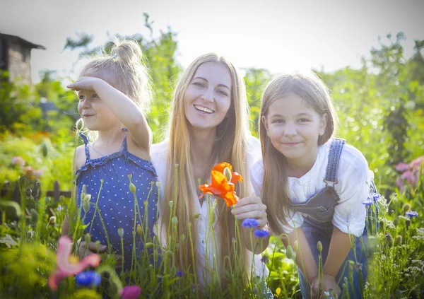 Glad kvinna och hennes döttrar i den blommande våren trädgård — Stockfoto