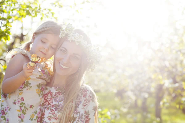 Madre felice e la sua figlioletta in un giardino fiorito — Foto Stock