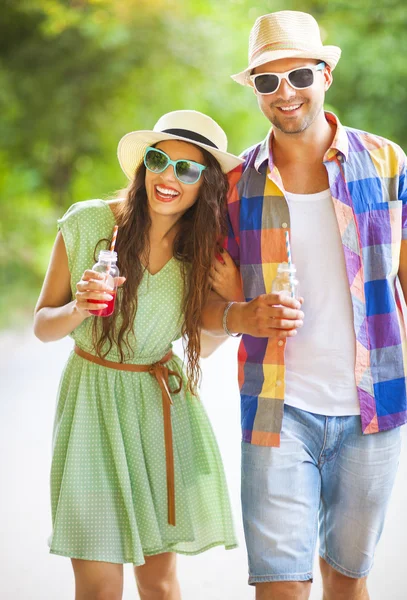 Happy young couple drinking juice and walking — Stock Photo, Image
