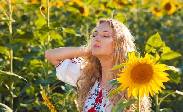 Frau in traditioneller Bluse hält Sonnenblume in Sonnenblume — Stockfoto
