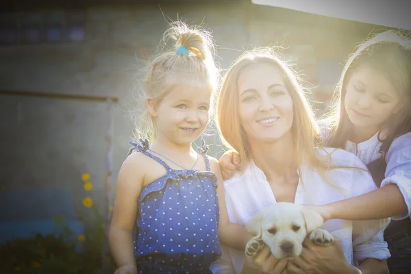 Šťastná žena a její dcery s štěně labrador — Stock fotografie