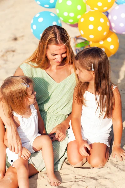 Femme heureuse et ses petites filles à la plage avec des ballons — Photo