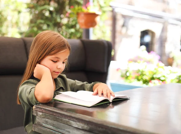 Bahçede bir kitap okuma bir sevimli küçük kız portresi — Stok fotoğraf