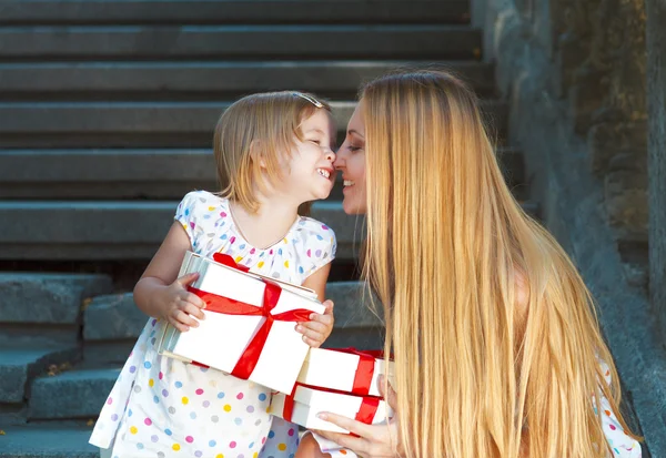 Cute little girl and her mother holding presents — Stock Photo, Image