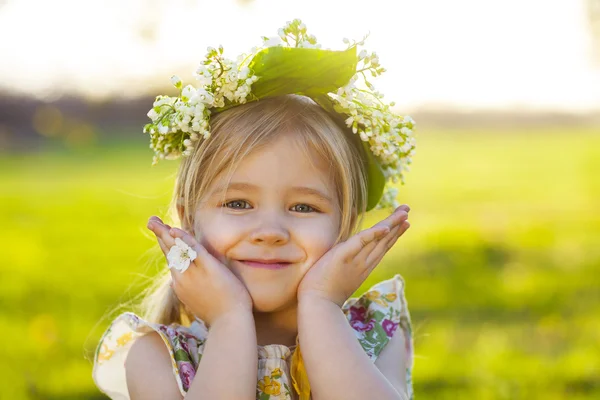 Söt liten flicka med blont hår i en krans av lily av vall — Stockfoto