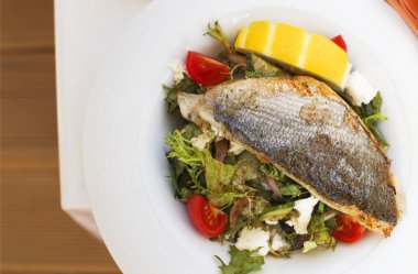 Sıcak bir tabakta dorado balık salatası