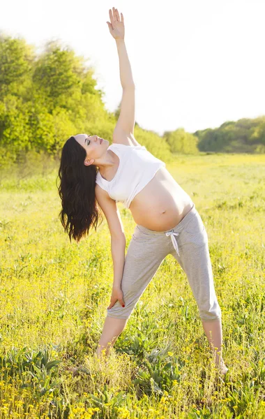 Pregnant woman doing yoga in nature outdoors — Stock Photo, Image