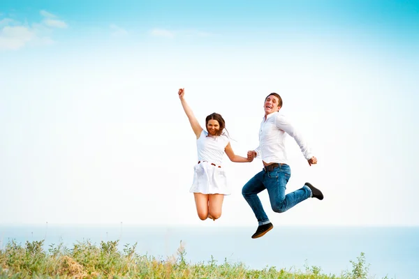 Young happy couple jumping on the beach — Stock Photo, Image