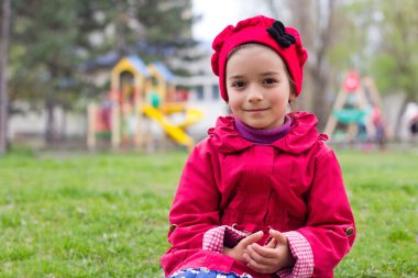 Bahar Bahçesi yeşil çimlere oturup küçük kız. Chil