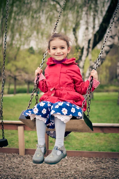 Cheerful little girl in red jacket and blue dress with flowers o — Stock Photo, Image