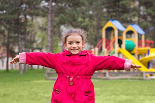 Little girl's portrait on playground. Child in red jacket in chi — Stock Photo, Image