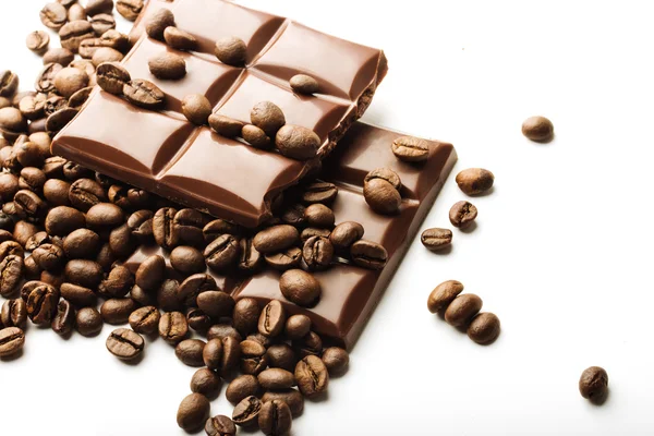 Kávová zrna a čokoládové figurky na bílém pozadí — Stock fotografie