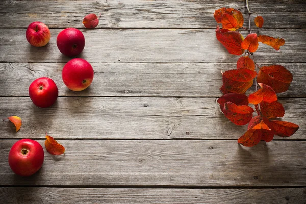 Red apples and leaves on old wooden background — Stock Photo, Image