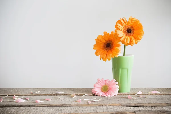 Gerbera in vase on old wooden table — Stock Photo, Image