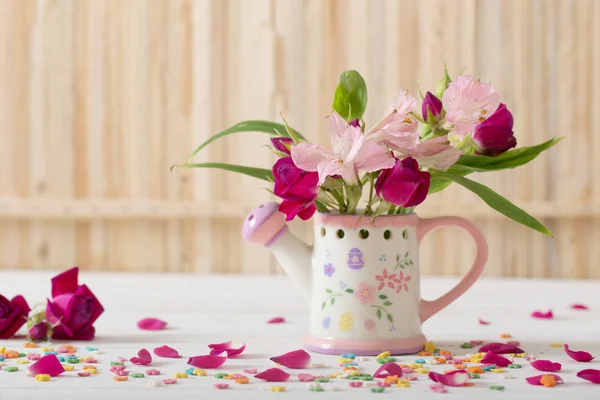 Blumenstrauß in Gießkanne auf hölzernem Hintergrund — Stockfoto