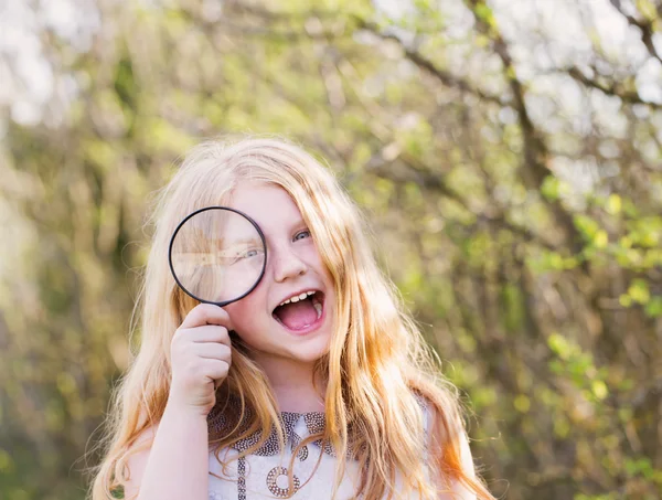 Portret van een schattig jong meisje op zoek via Vergrootglas een — Stockfoto