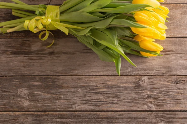 Tulipanes amarillos sobre fondo de mesa de madera — Foto de Stock