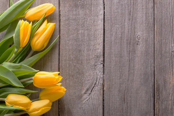 Yellow tulips over wooden table background — Stock Photo, Image