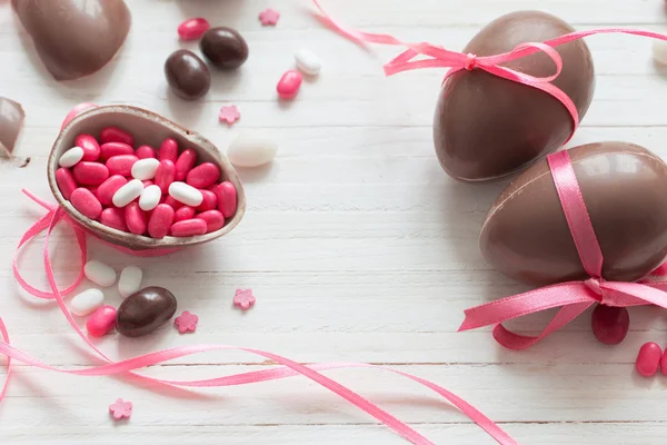 Шоколад и розовые пасхальные яйца на белом фоне — стоковое фото