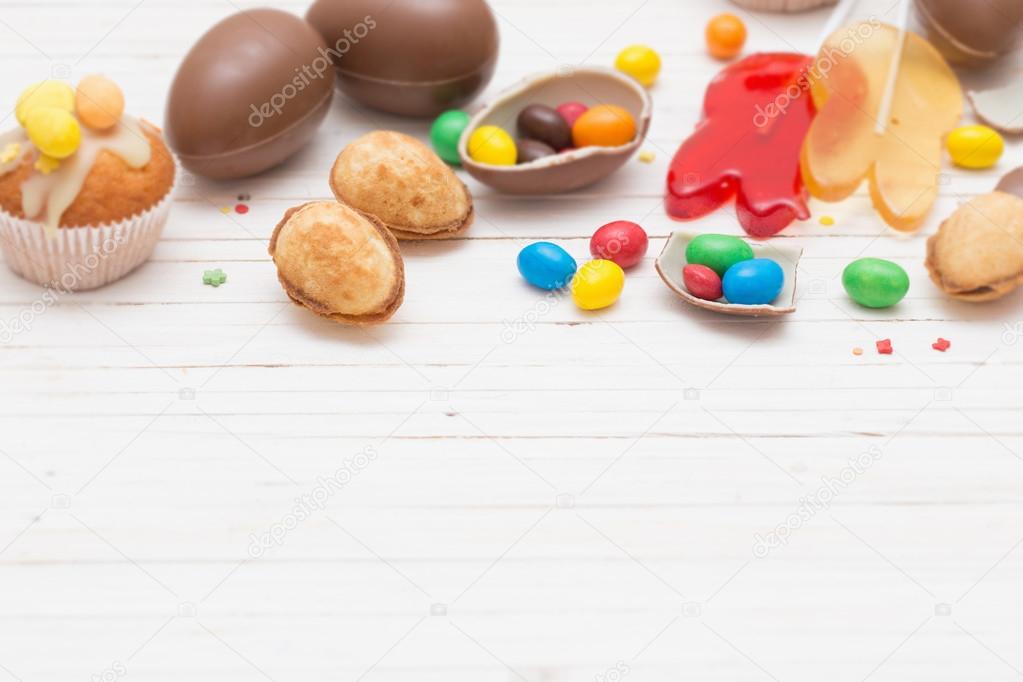 Chocolate Easter Eggs and Cupcake Over Wooden Background