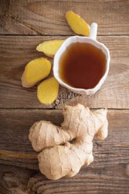 Ahşap arka plan üzerinde beyaz bir fincan çay zencefil