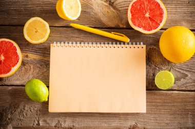 eski ahşap masa üstünde defter ile narenciye