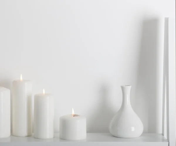 white candles burning on a white shelf