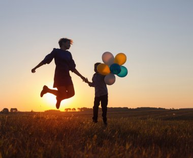 mutlu anne ve oğlu balonlarla açık atlama