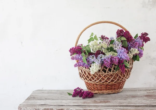 Basket with a branch of lilac flower — Stock Photo, Image