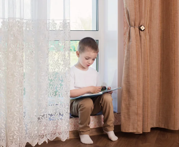 Child on windowsill reading book — Stock Photo, Image