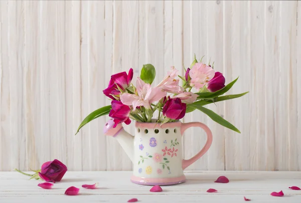 Μπουκέτο με φωτεινά λουλούδια στο πότισμα μπορεί σε ξύλινα φόντο — Φωτογραφία Αρχείου